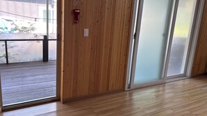 A wooden interior with a sliding glass door, a fire alarm, and a view of the outside. - MAUMAEGOHYANG Pension (Cheongdo)