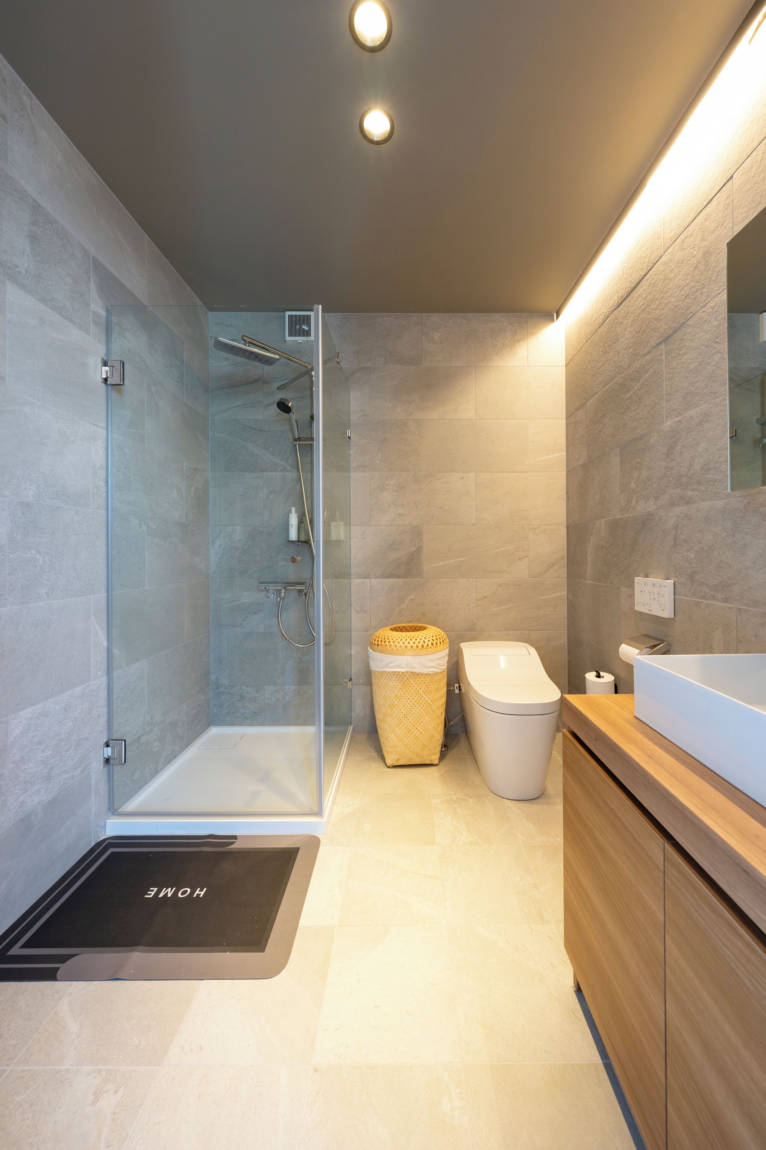 A modern bathroom with a glass shower enclosure, a wooden vanity, and a built-in toilet.