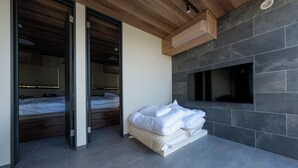 A modern bedroom with a bed, a TV mounted on the wall, and a wooden ceiling. - AKESUKE (Minamiawaji)