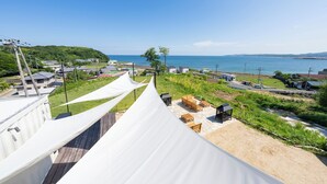 A beachside view with a white tented area, outdoor seating, and a clear view of the sea. - AKESUKE (Minamiawaji)