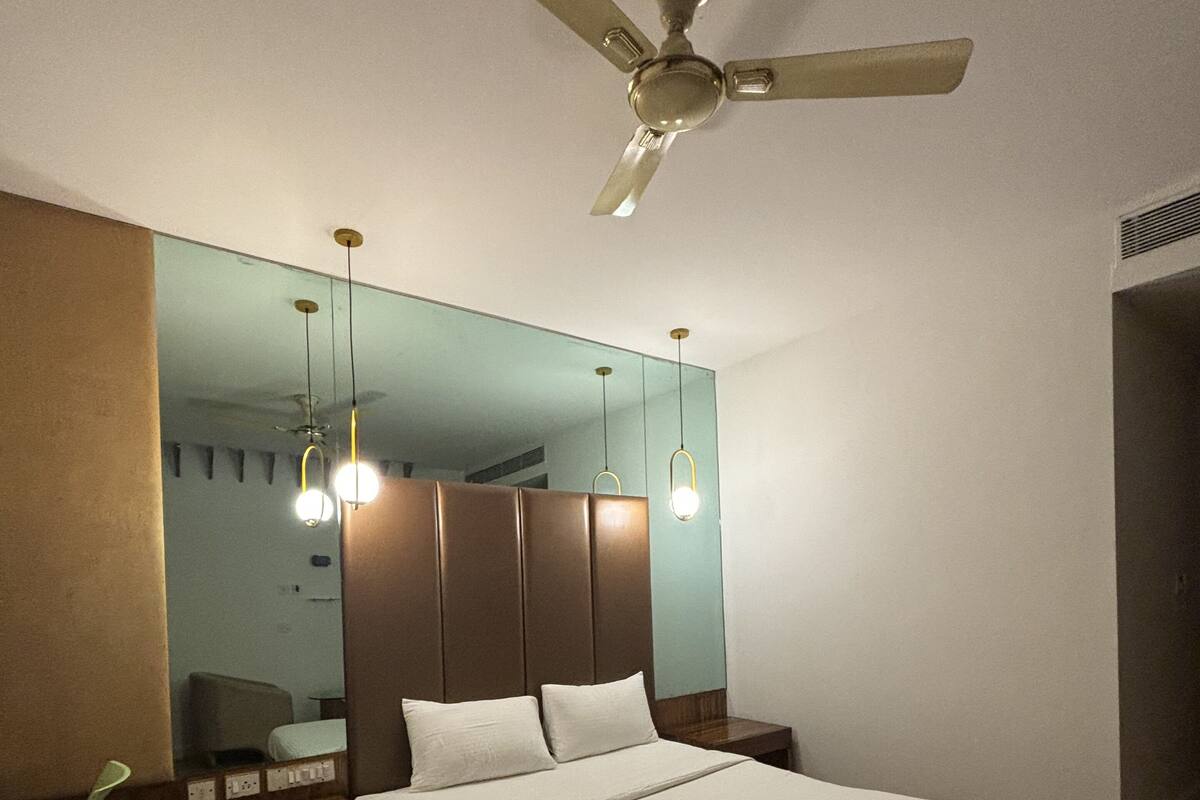 A bedroom with a bed, a nightstand, a chair, a ceiling fan, and a mirror.