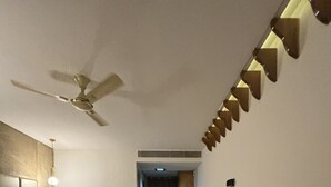 Habitación de hotel con dos camas, ventilador de techo, una mesita y una silla.