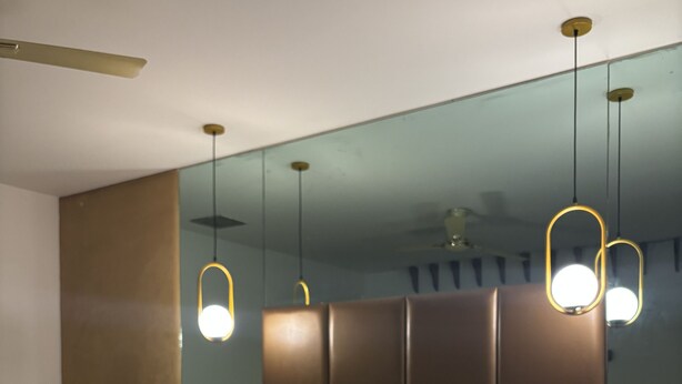 Una habitación de hotel con cama, escritorio y silla. Hay lámparas colgantes sobre la cama.