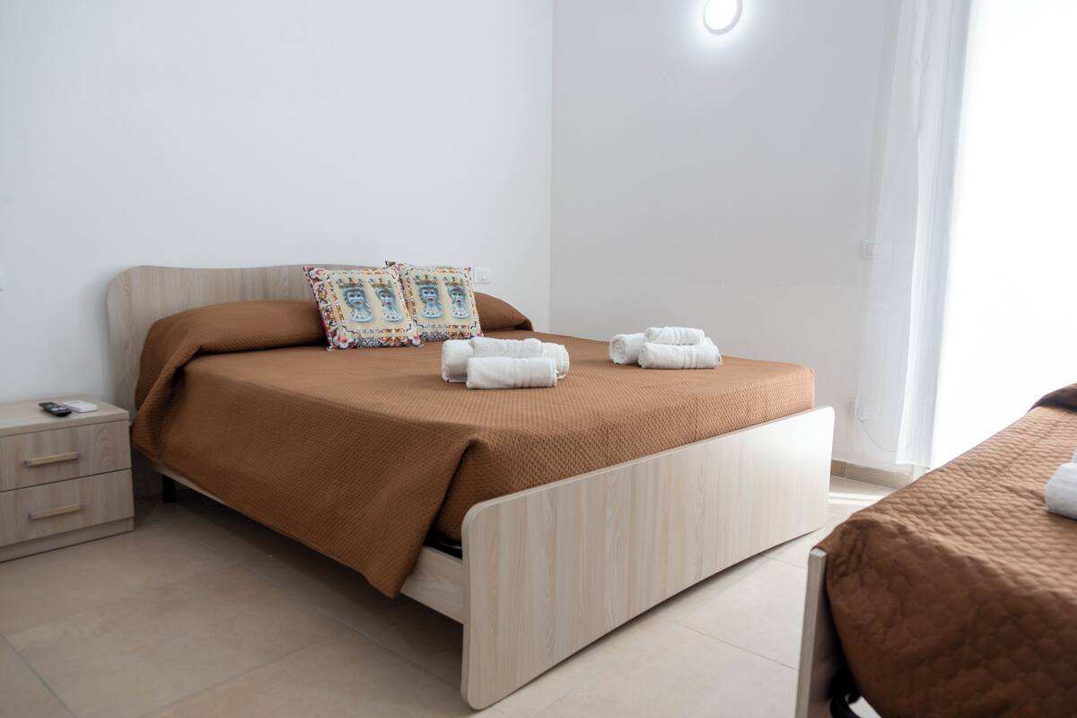 A modern bedroom with a bed, a nightstand, and a bedside table.