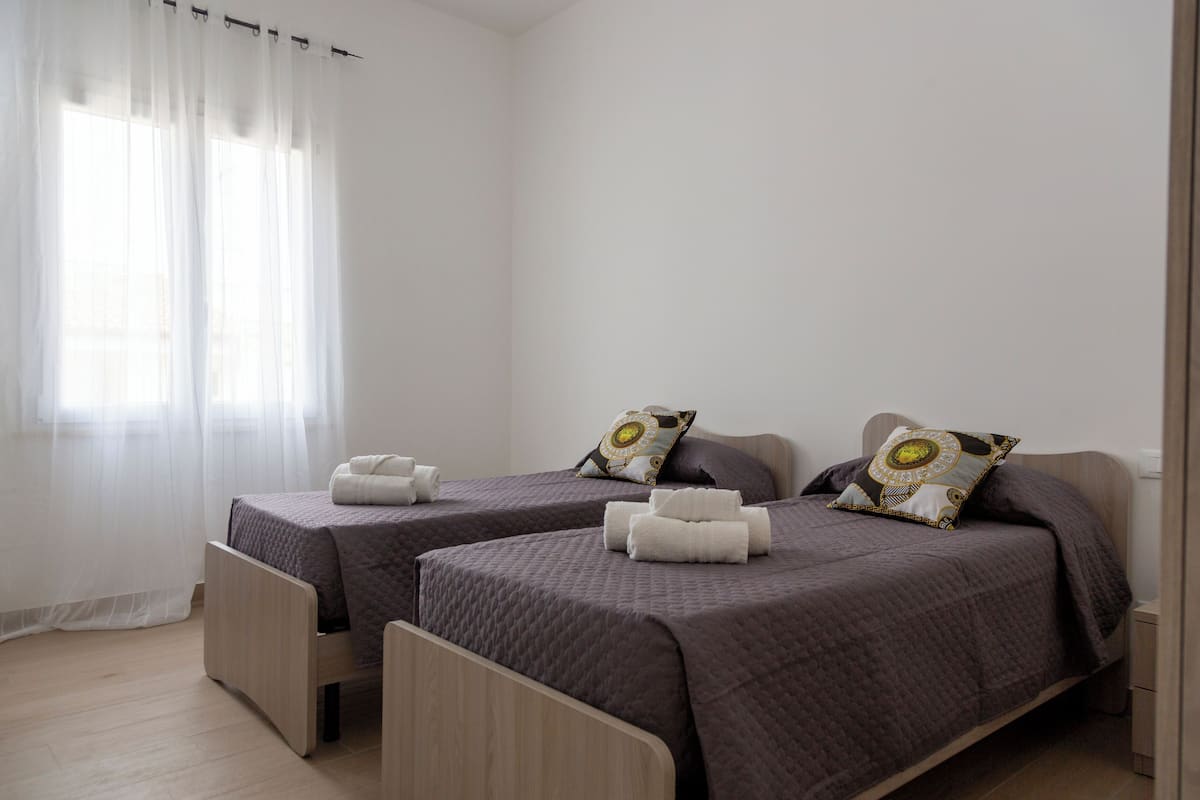 A bedroom with two single beds, each with a pillow and a blanket.