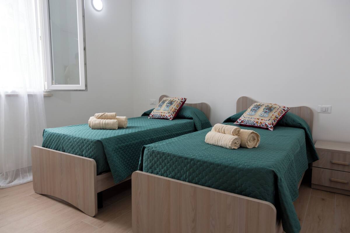 Two single beds with green bedding, wooden headboards, and matching pillows.