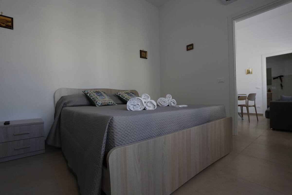 A modern bedroom with a bed, a nightstand, and a chair.