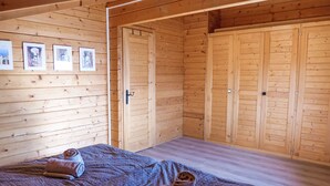 Een houten kamer met een bed, twee handdoeken en een muur met ingelijste foto’s.