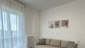 Una sala de estar con un sofá, una mesa de centro y un radiador. Hay tres cuadros enmarcados en la pared.