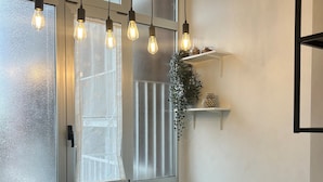 Un comedor moderno con una mesa negra y sillas blancas, ventanas grandes con vidrio esmerilado y lámparas colgantes.
