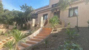 A building with a staircase leading up to a door, surrounded by greenery and a clear sky. - Lovely Mas provençal on the route de Pagnol. Sleeps 10/12. (Marseille)