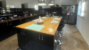 A modern kitchen with a central island, pendant lighting, and a clock on the wall. - Lovely Mas provençal on the route de Pagnol. Sleeps 10/12. (Marseille)