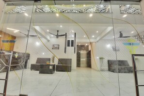Un intérieur moderne avec une cloison en verre, des ventilateurs de plafond et un espace d’accueil comprenant un canapé et un bureau.