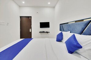 Une chambre d’hôtel avec un lit, un téléviseur fixé au mur et une porte.