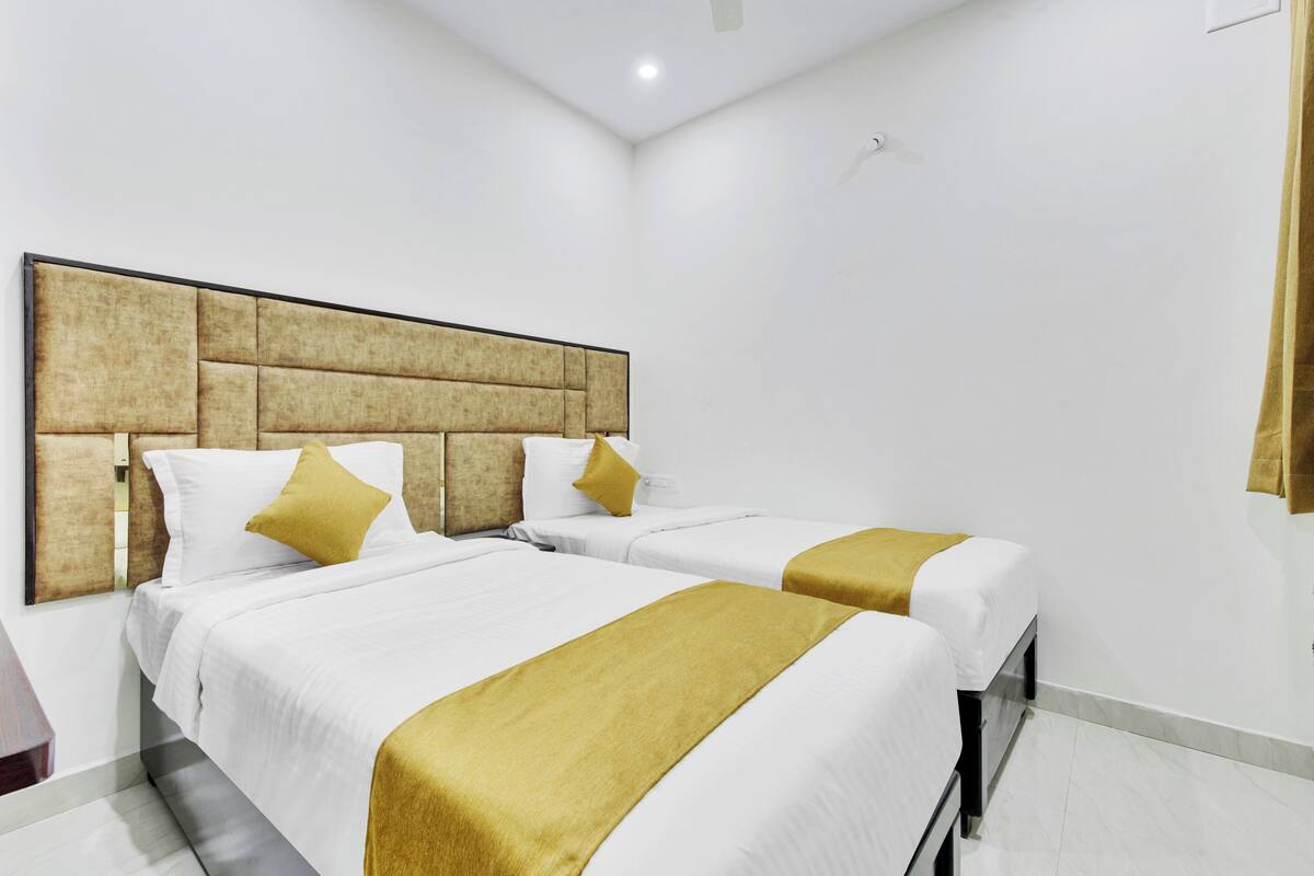 Une chambre d’hôtel avec deux lits, une grande tête de lit et une décoration aux couleurs neutres.