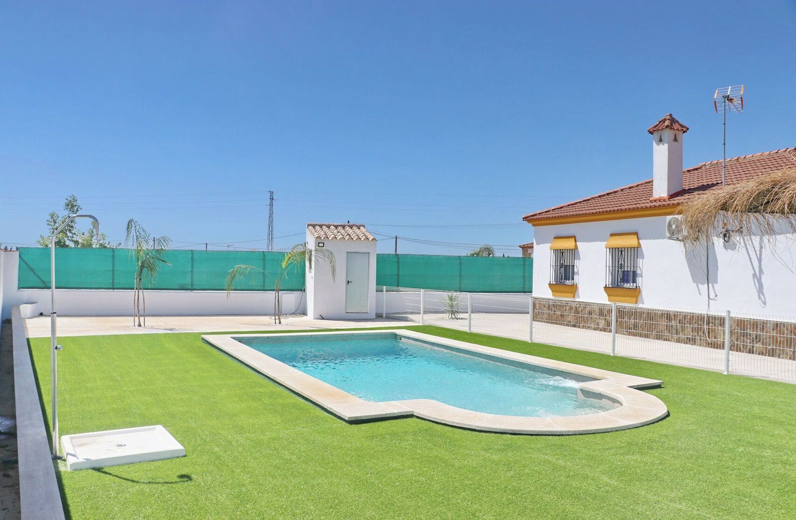 A rectangular swimming pool with a white border, surrounded by green artificial grass.