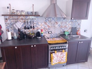 Een koelkast, een oven, een kookplaat, kookgerei, borden en bestek