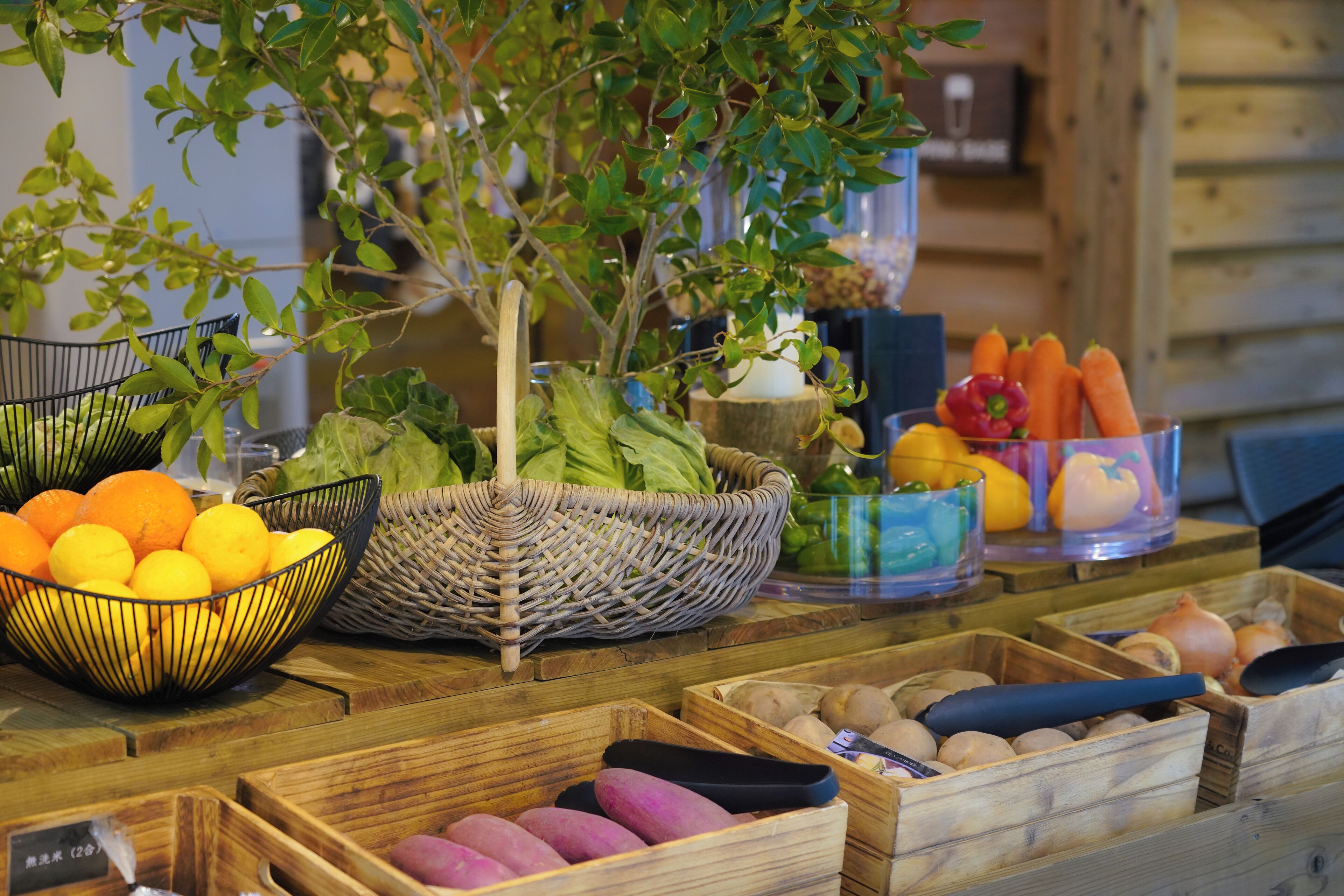 A wooden table with various fruits and vegetables, including oranges, carrots, and potatoes.