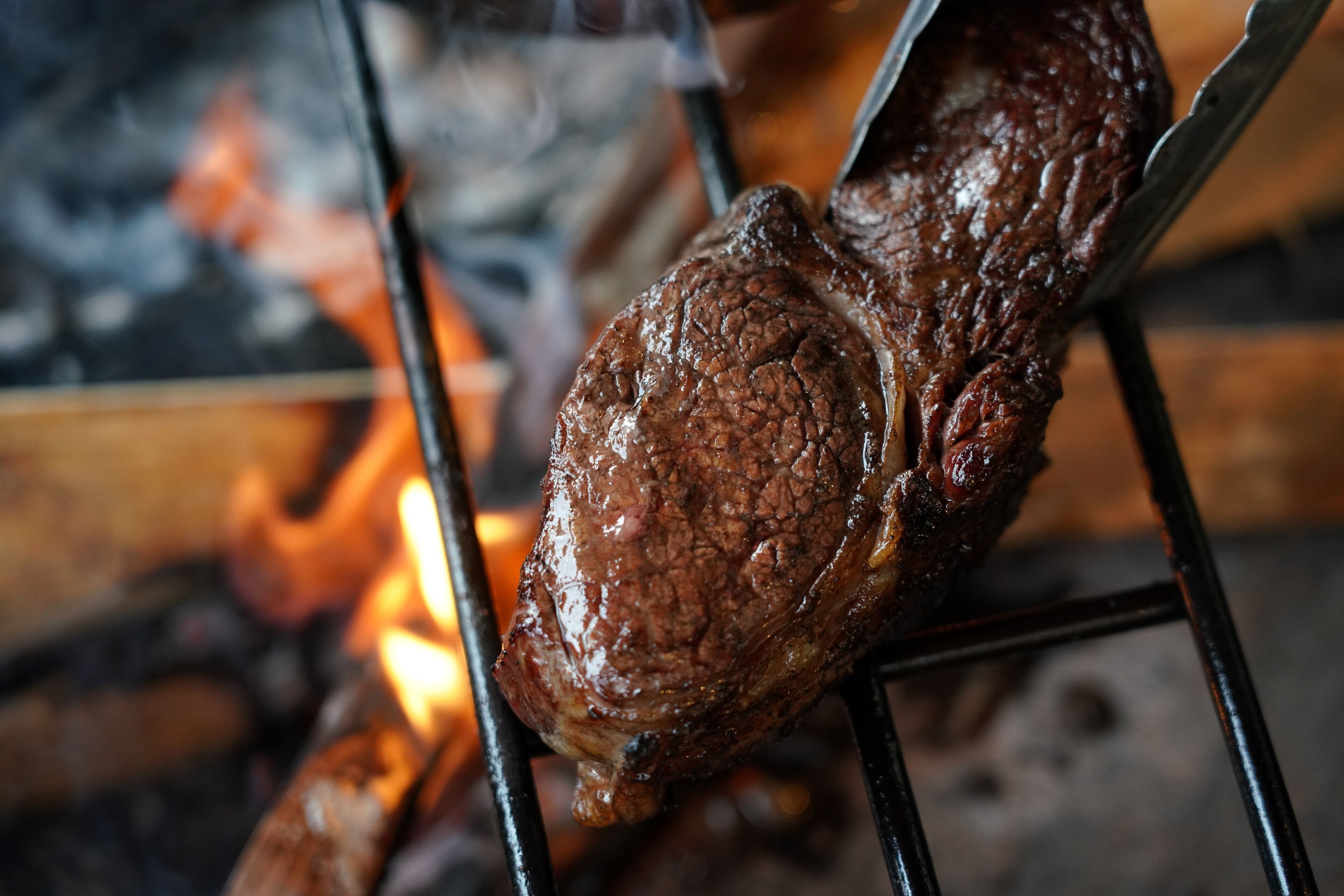A grilled steak on a metal rack over an open flame.