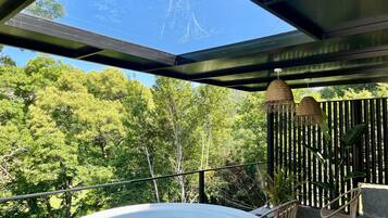 Un jacuzzi en un balcón con vistas a un bosque.