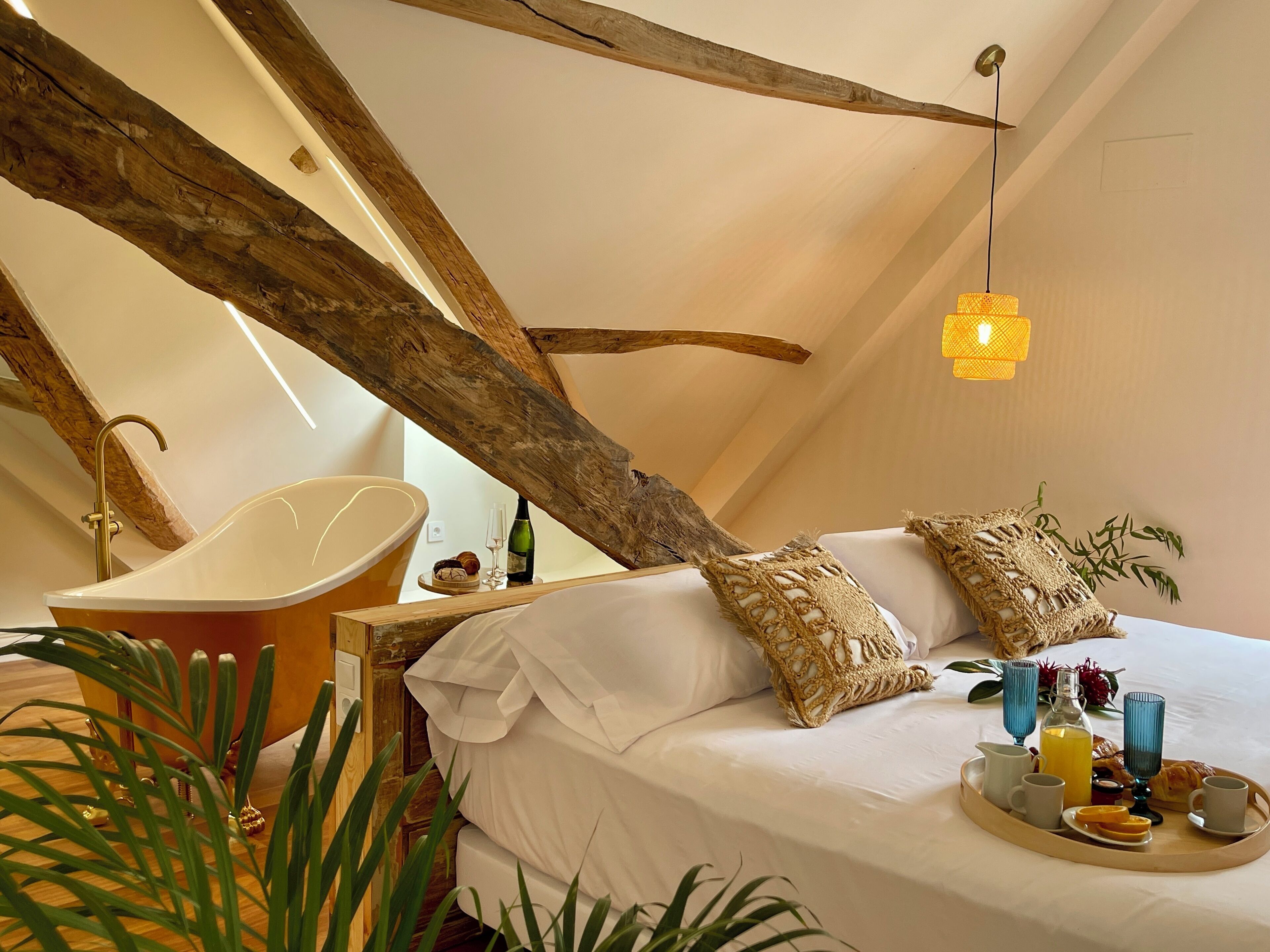 A cozy bedroom with a large bed, a bathtub, and a tray with breakfast items.