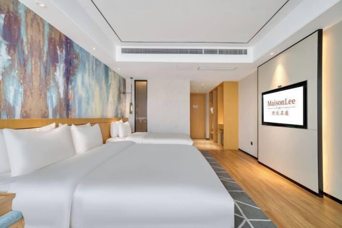 Ein modernes Hotelzimmer mit einem großen Bett, einem Bild an der Wand und einem Schild mit dem Hotelnamen.