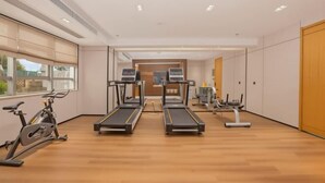 Une salle de sport équipée de tapis de course, de vélos d’appartement et d’autres appareils d’exercice.