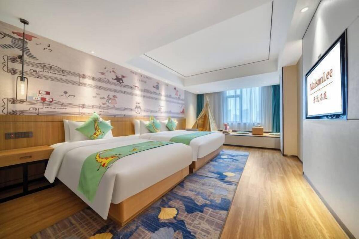 Ein Hotelzimmer mit zwei Betten, einer großen Wandmalerei, einem Fernseher und einem Fenster mit Vorhängen.
