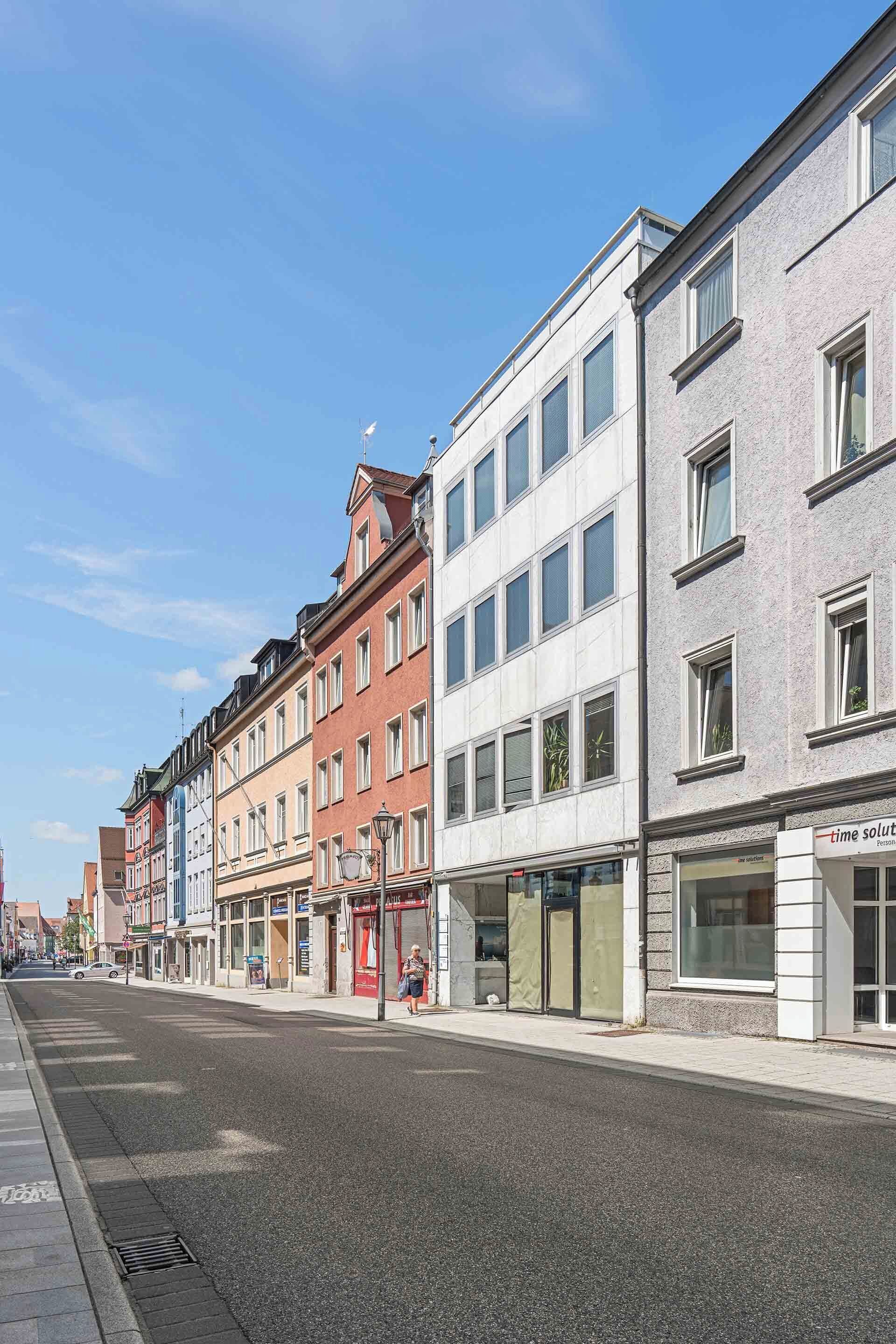 A street with multi-story buildings, including a shop with a sign that reads "time solution".