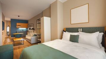 Quarto de hotel com cama grande, sofá, mesa de jantar e cozinha compacta.