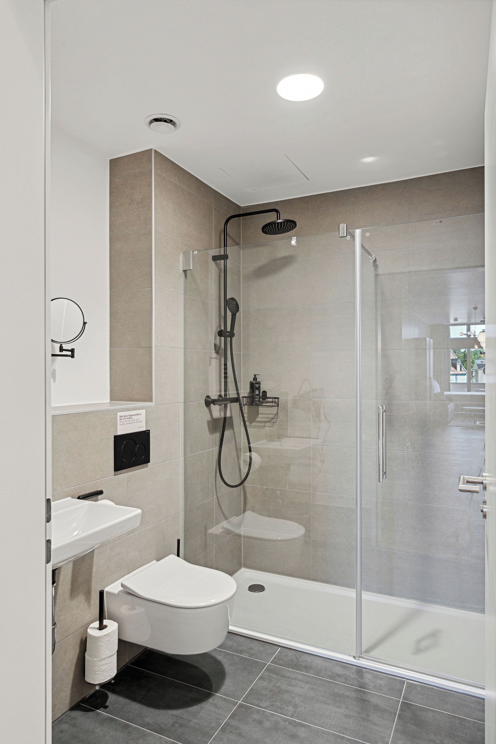 Un baño moderno con ducha de vidrio, inodoro y lavamanos.