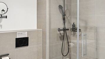 Une salle de bain moderne dotée d’une douche à parois de verre, de toilettes et d’un lavabo.