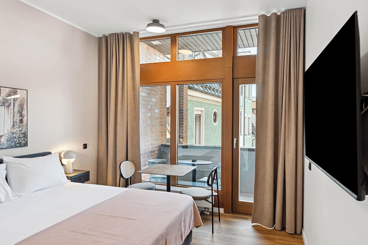Una habitación de hotel con cama, escritorio, silla y televisión.