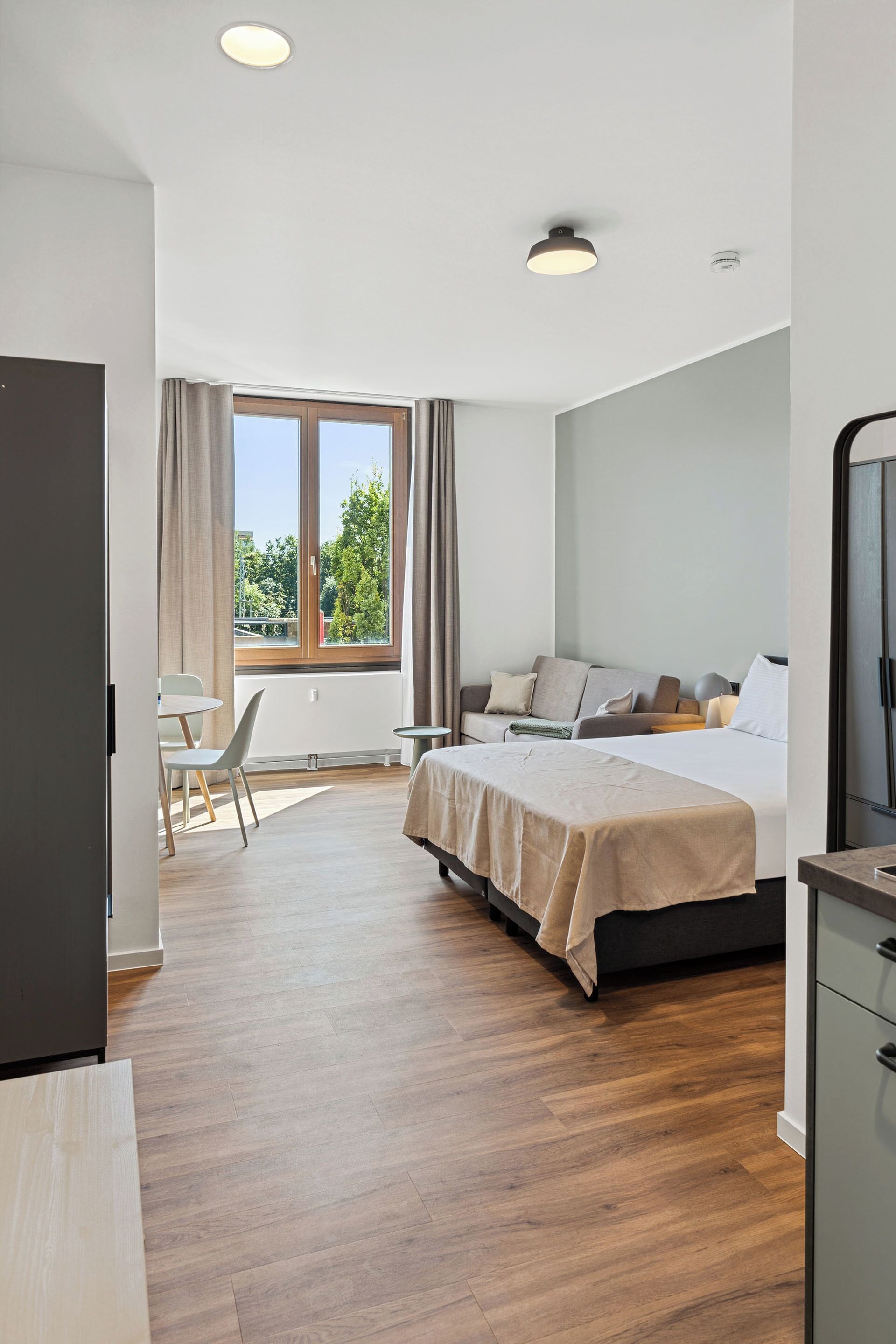 Ein modernes Hotelzimmer mit einem großen Bett, einem Schreibtisch und einem Fenster mit Blick ins Freie.