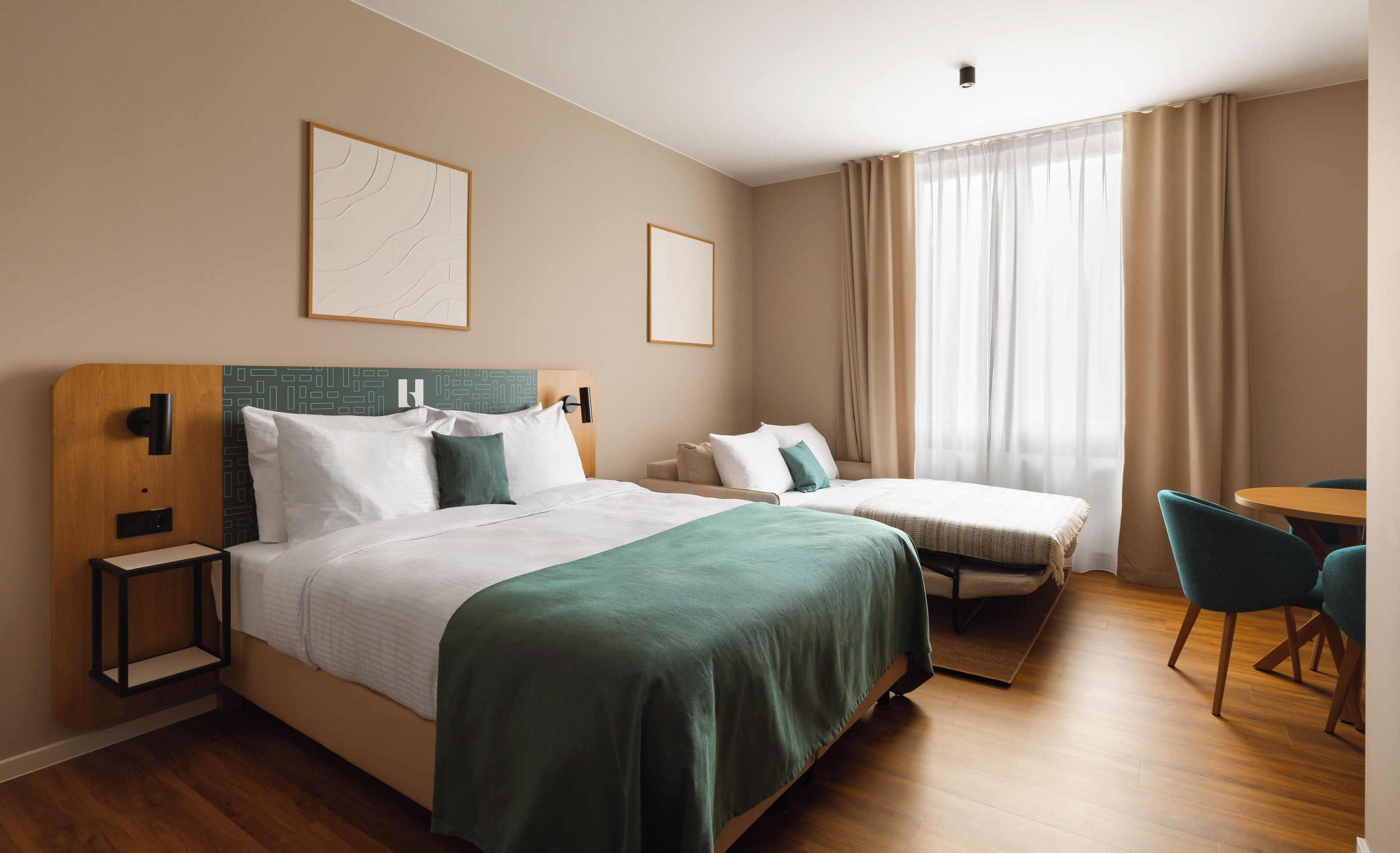 Ein Hotelzimmer mit zwei Betten, einem Schreibtisch und einem Stuhl.