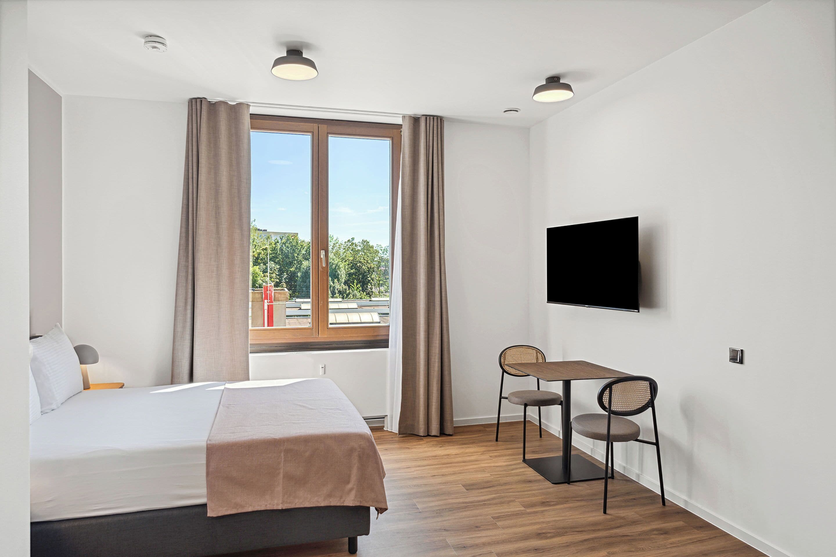Une chambre d’hôtel moderne équipée d’un lit, d’un bureau et d’une télévision.