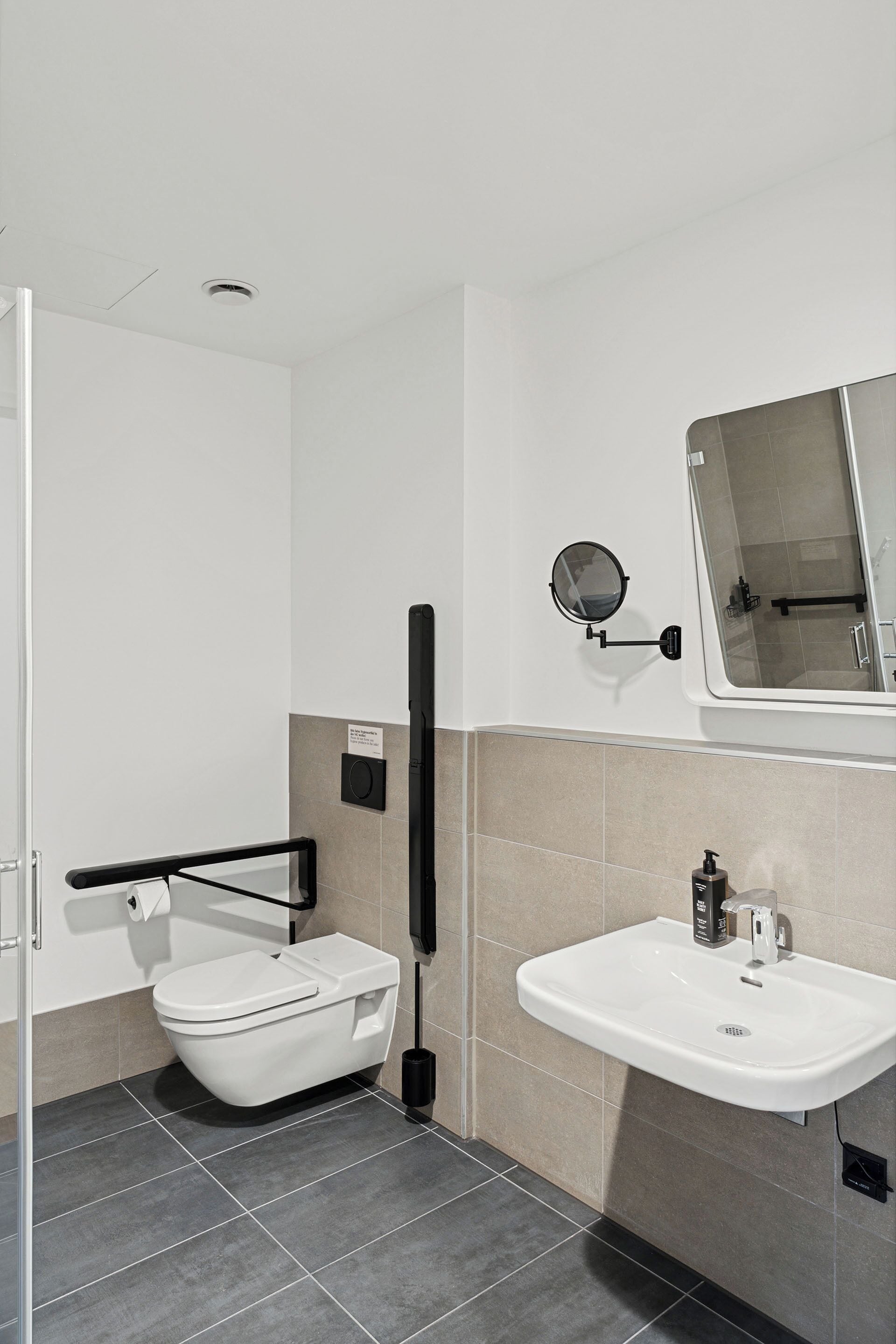 A modern bathroom with a toilet, sink, and mirror.