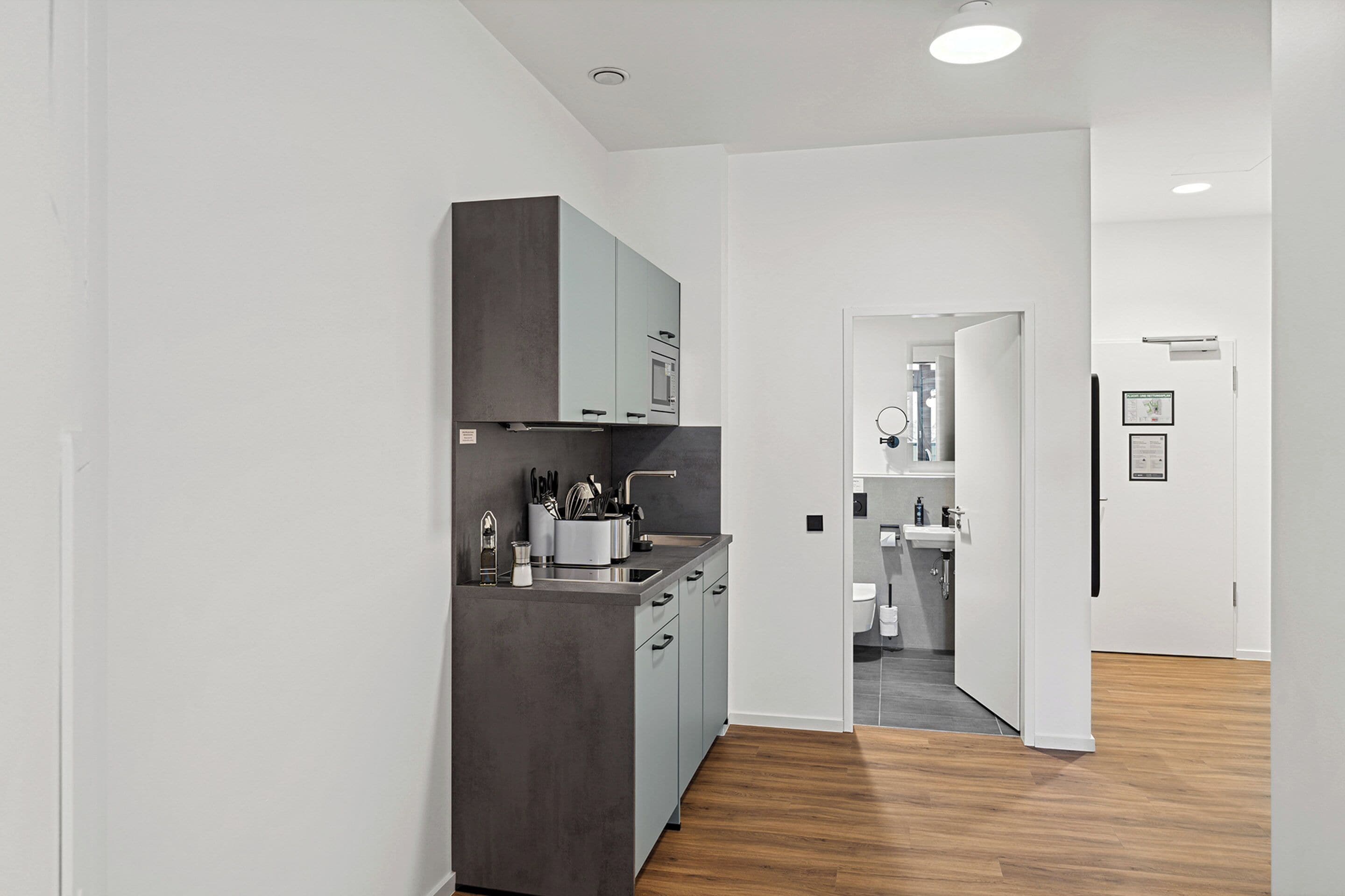 Une cuisine moderne avec des meubles gris, un four encastré et un évier.