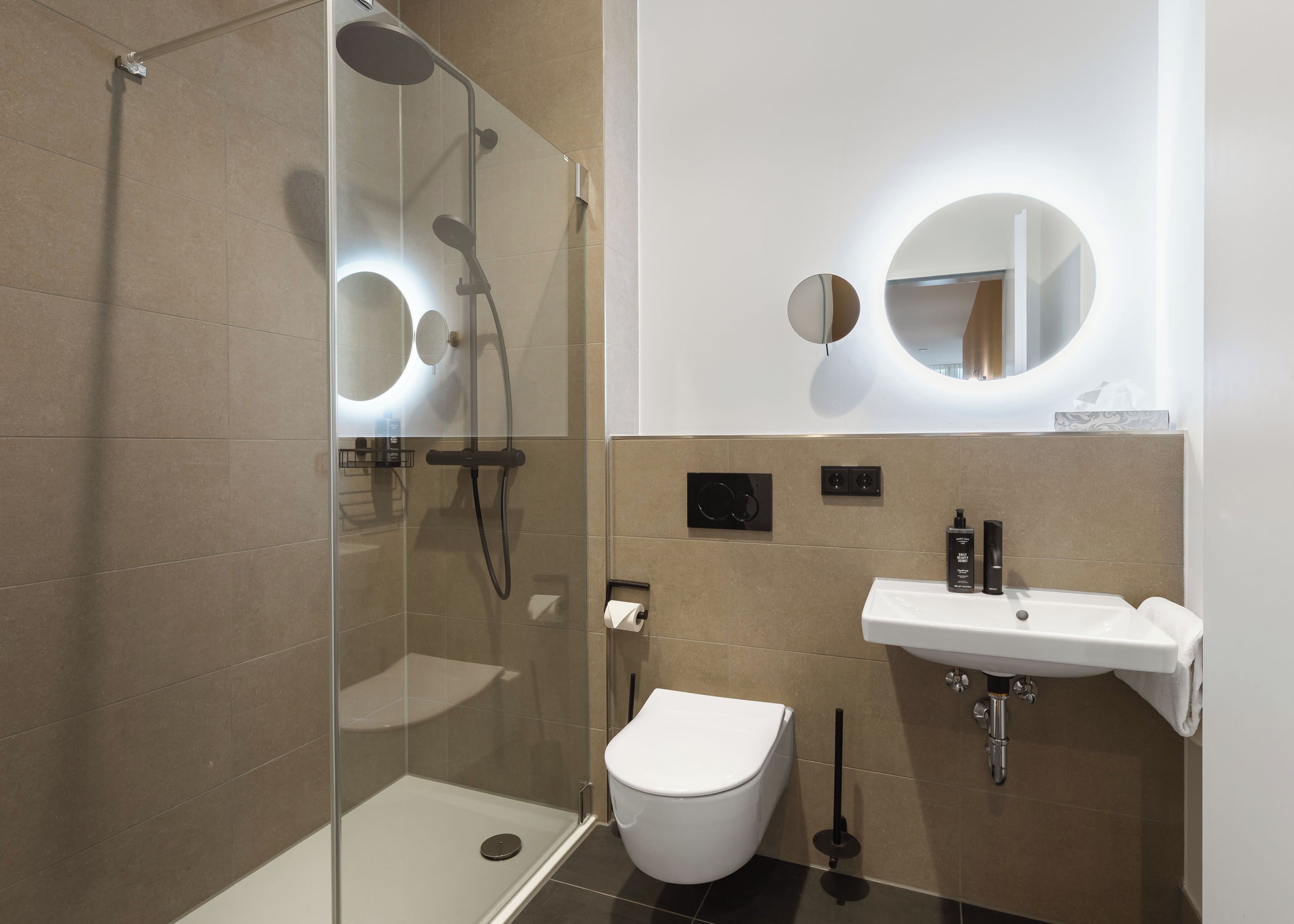A modern bathroom with a glass-enclosed shower, a white toilet, and a sink with a mirror above it.