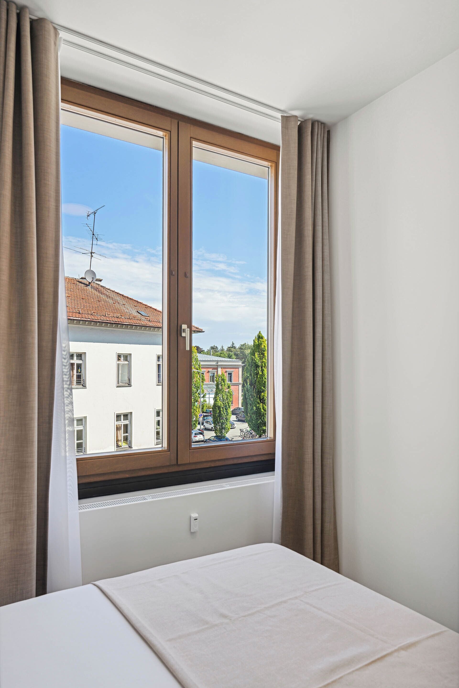 Una habitación de hotel con un ventanal grande, una cama y vistas a la ciudad.