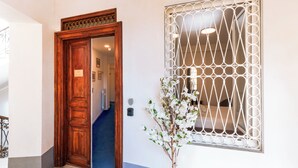 A wooden door, a white wall, and a window with a geometric pattern. - Elysium Suites Colosseo (Rome)