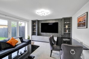 Relax in this stylish living room with a large flat-screen TV, comfortable sofa, and dining area.