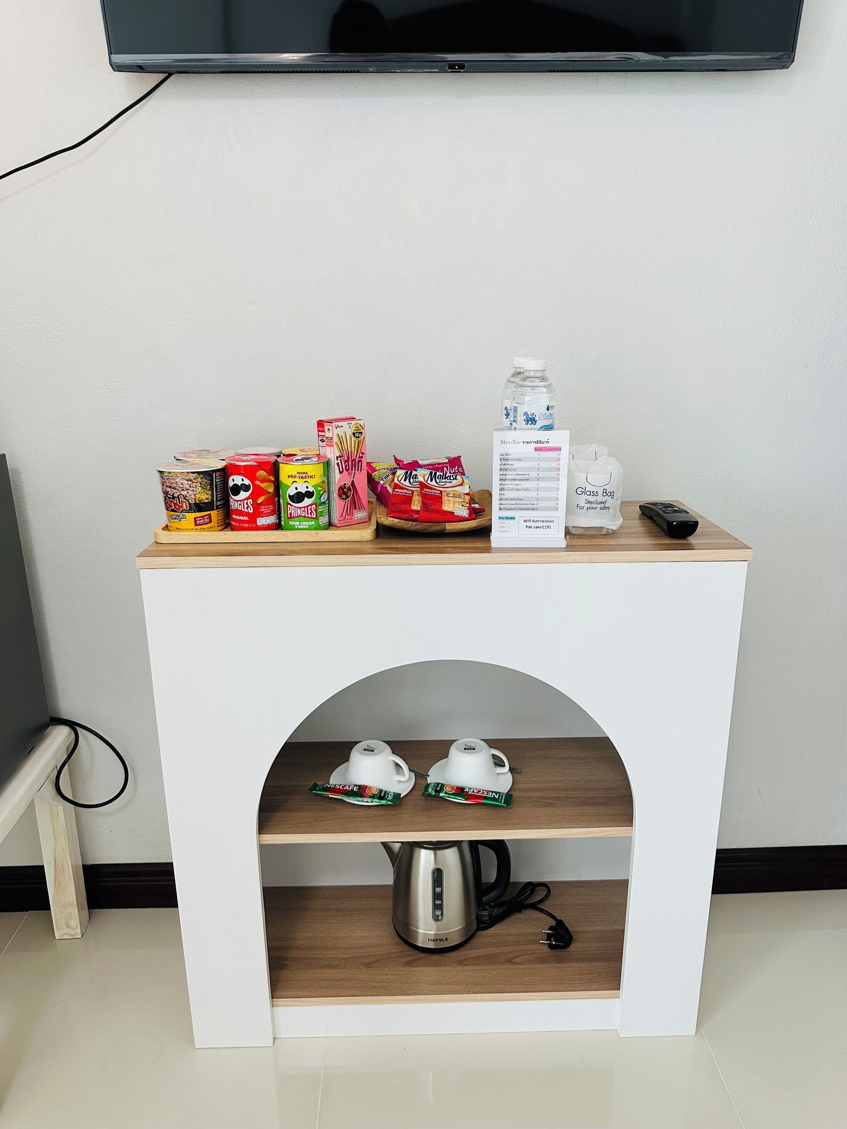 A small white table with a wooden top, a shelf below, and a TV mounted on the wall above.
