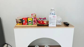 A small white table with a wooden top, a shelf below, and a TV mounted on the wall above.