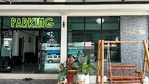 A building with a 'PARKING' sign, a reception area, and a swing set outside. - Service apartment lampang (Lampang)