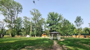 Um parque com um coreto, mesas para piquenique e uma área de recreação coberta.