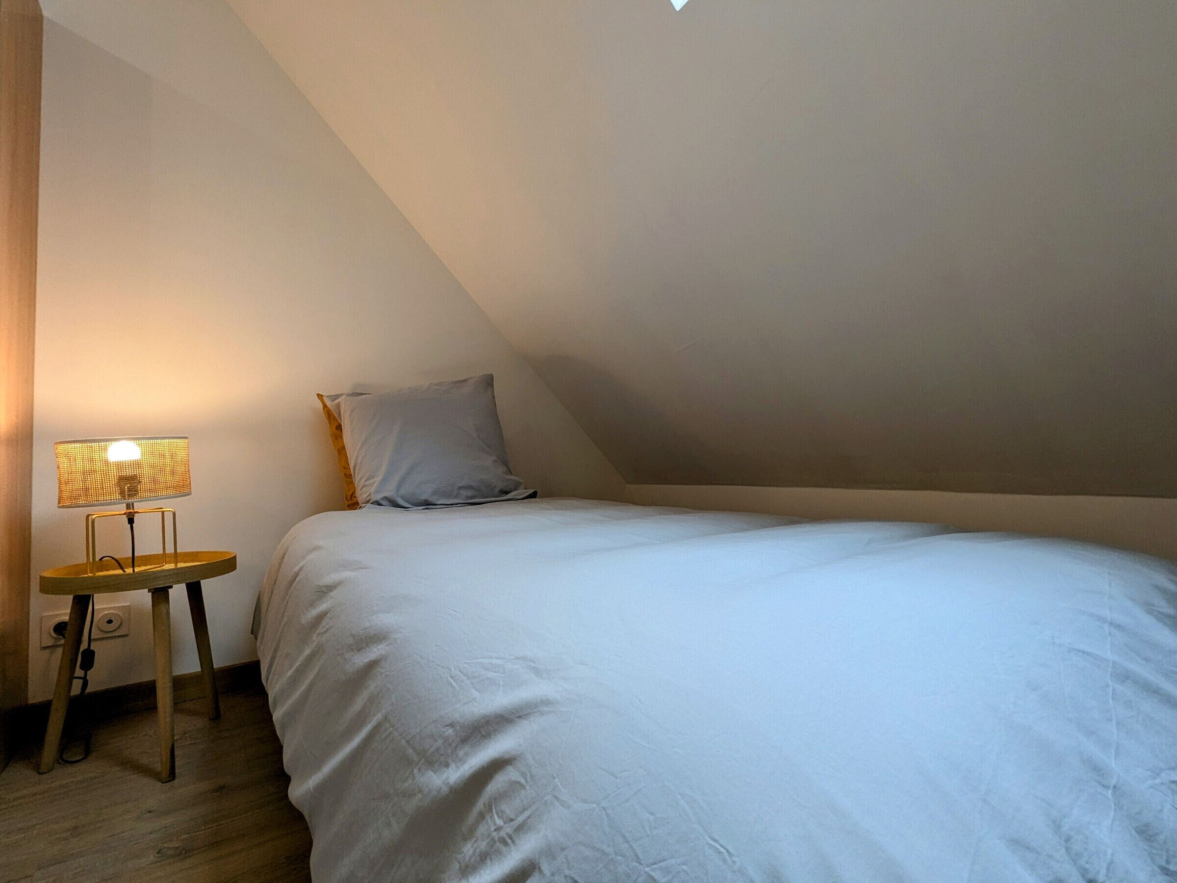 Un dormitorio con una cama, una mesita de noche y una lámpara.