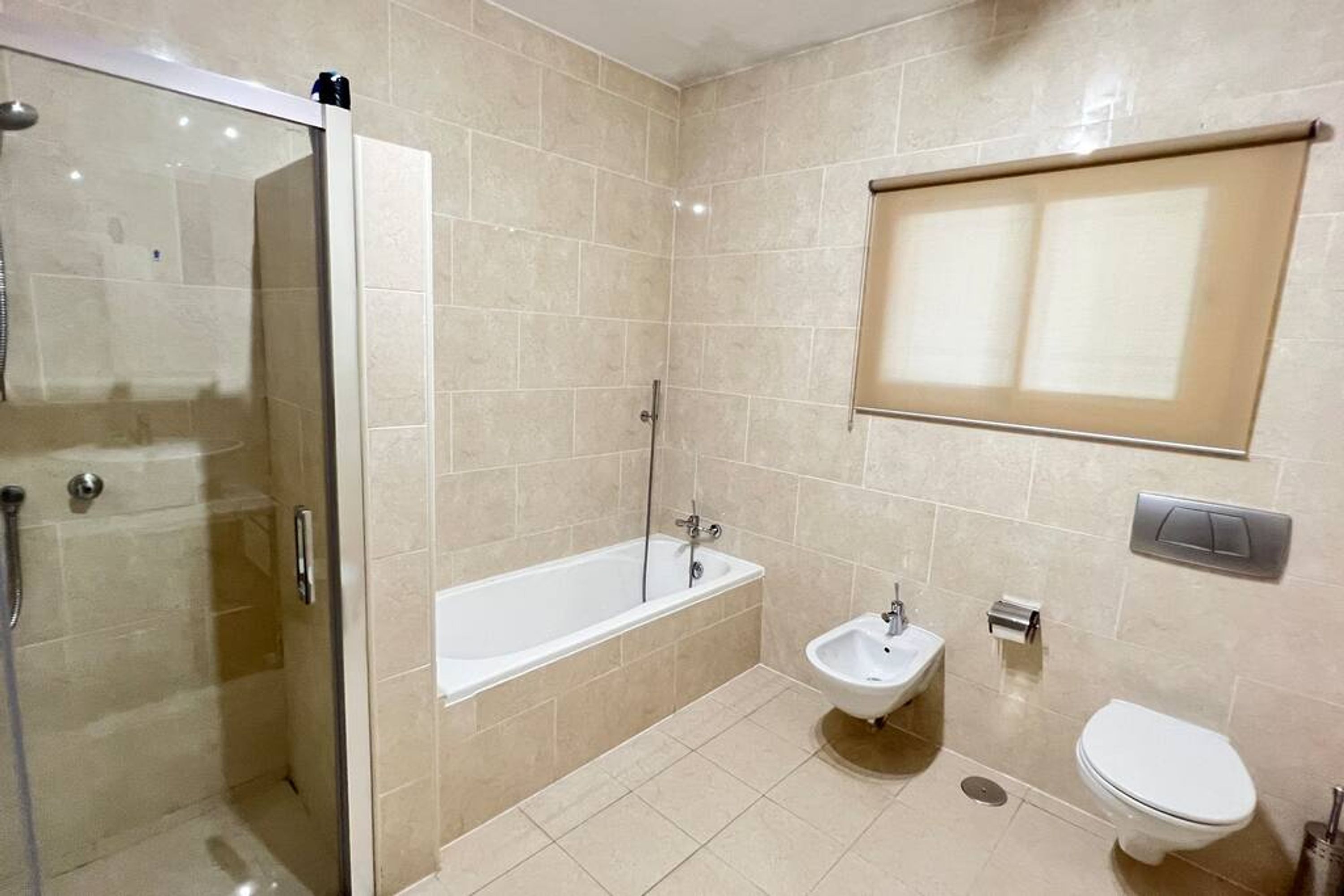 A modern bathroom with a glass-enclosed shower, a freestanding bathtub, a pedestal sink, and a toilet.