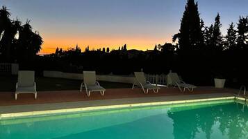 Relax by the serene pool surrounded by lush greenery and lounge chairs.