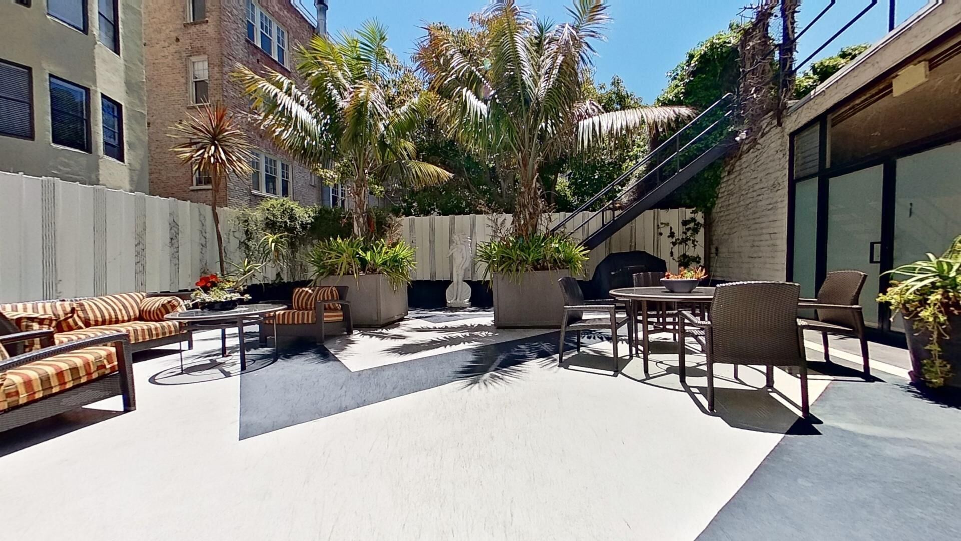 An outdoor patio with seating, plants, and a staircase.